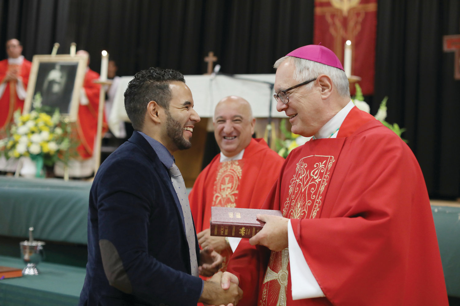 New teachers and faculty, as well as those celebrating special anniversaries at the school were honored by Bishop Tobin and Father Robert L. Marciano, president of Bishop Hendricken. Above, at right new school counselor and theology teacher Billy Burdier recieves a Bible from Bishop Tobin.